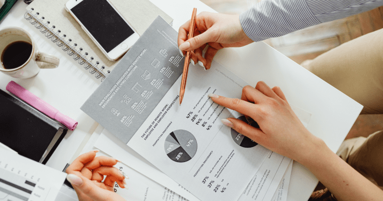 Discussing finances with a colleague over financial data with documents on the table. Get in touch with our accounting firm in Sydney for expert advice.