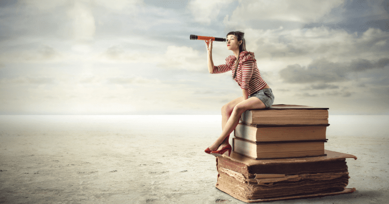 A woman using binoculars while sitting on top of stacked books. Contact our accounting firm in Sydney for expert financial advice and bookkeeping services.