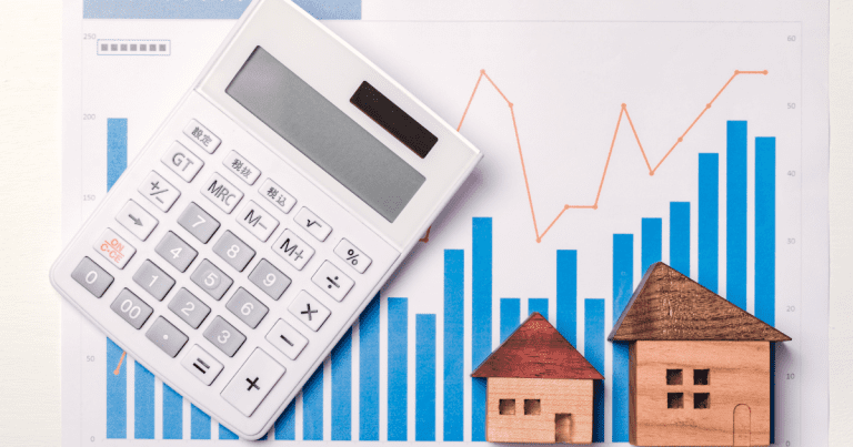 A calculator and miniature houses on a table with financial data analysis results in the background. Let our team of business accountants in Sydney help you with investment strategies and wealth management.