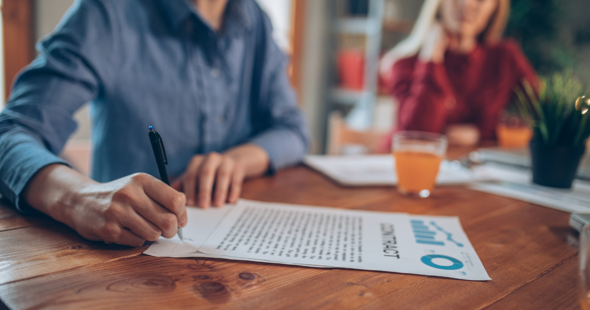 A man signing a contract. Don't forget to have a professional tax accountant review the terms before signing.