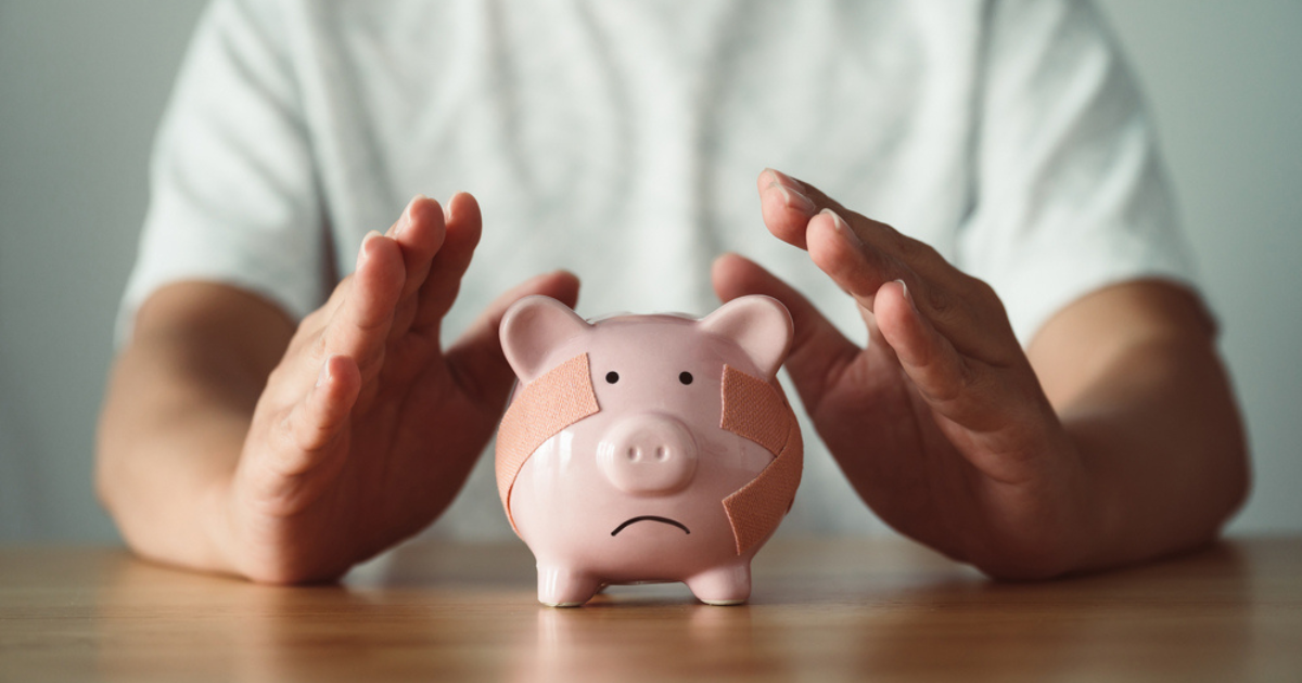 A man reaching out to a sad piggy bank with bandages on its body. Our small business accountants can help you with financial planning to prevent financial hardship.