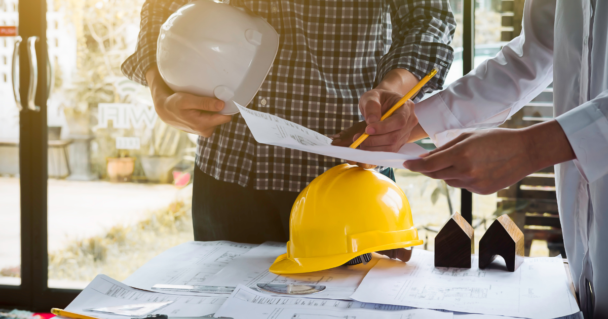 Two men in a construction setting with two helmets and miniature houses on top of the table. Trust our small business accountants in Sydney to help you manage your finances.