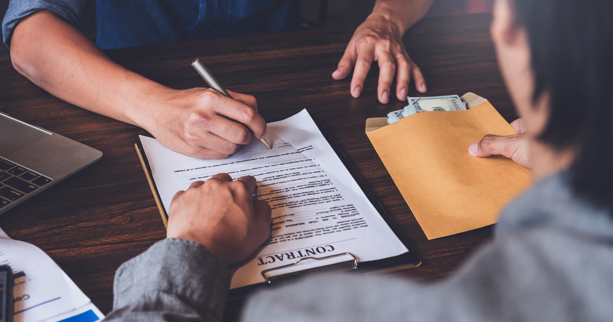 A person signing a contract while another person holds an envelope filled with money. Trust our business accountants in Sydney to help you manage your finances and ensure compliance with financial regulations.