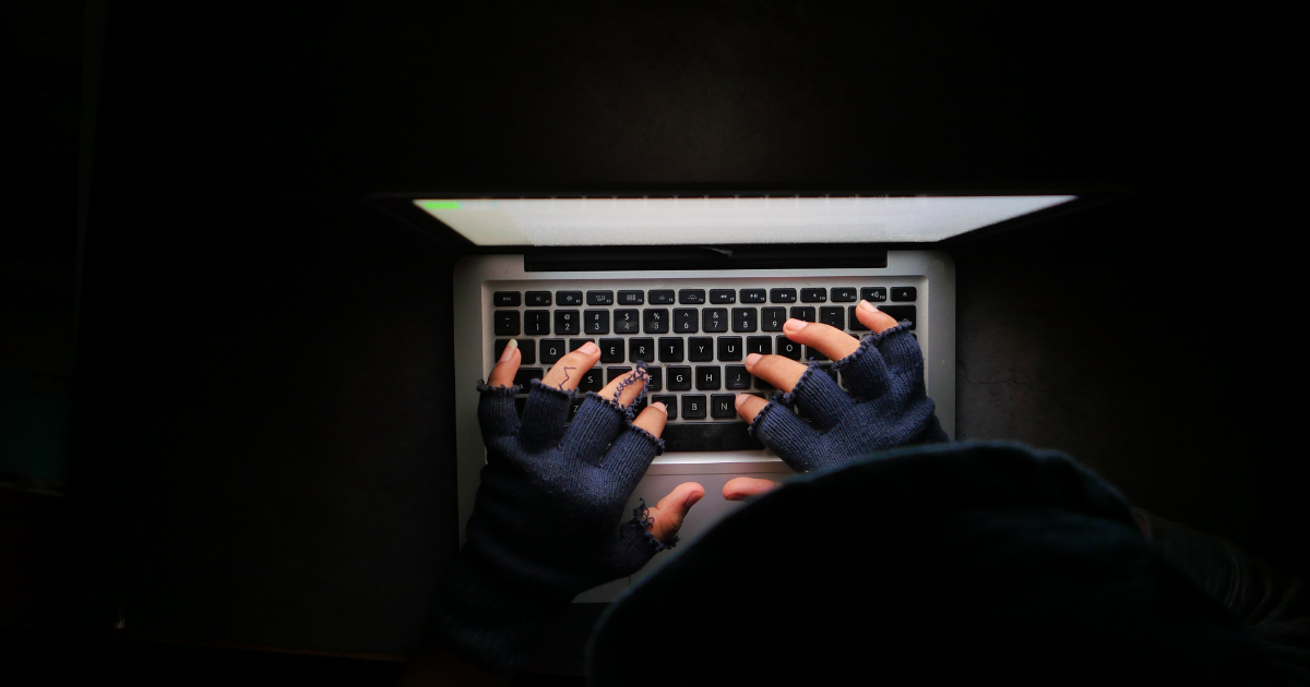 A hooded individual working on a laptop in a dark setting. Trust our small business accountants in Sydney to help you manage your finances and ensure compliance with tax regulations.