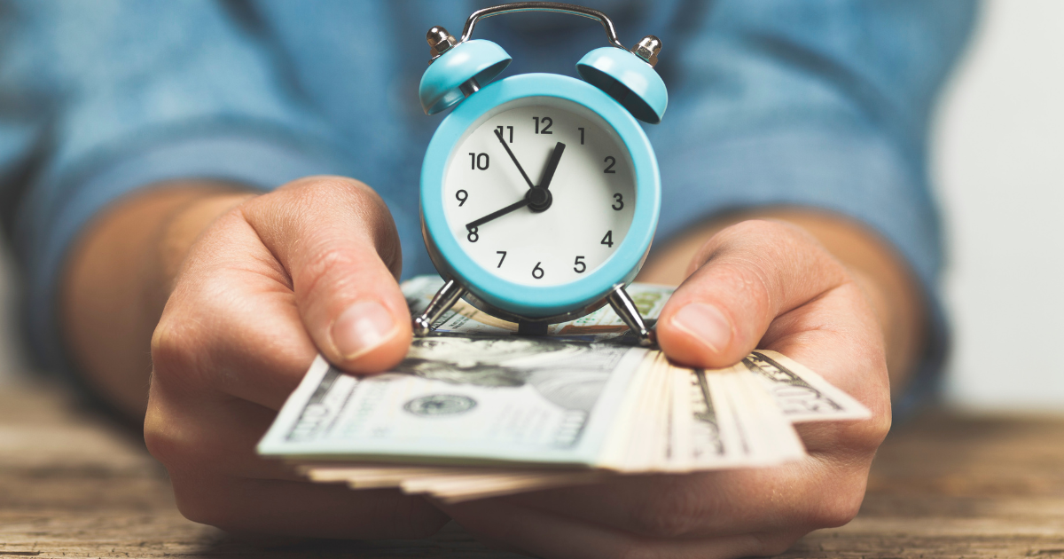 A person holding a stack of dollar bills with a clock sitting on top. Contact our small business accountants in Sydney to help you manage your finances and stay on top of tax deadlines.