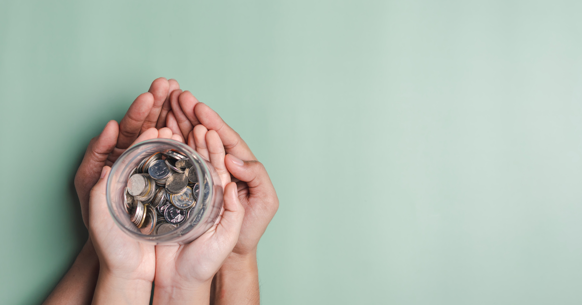 Two pairs of hands are holding a glass jar filled with coins. Get help managing your finances with our team of experienced accountants in Sydney.