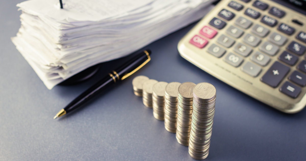 Layered coins, a pen, a calculator, and documents for financial planning piled up. Our small business accountants in Sydney can assist you with bookkeeping, tax planning, and more.