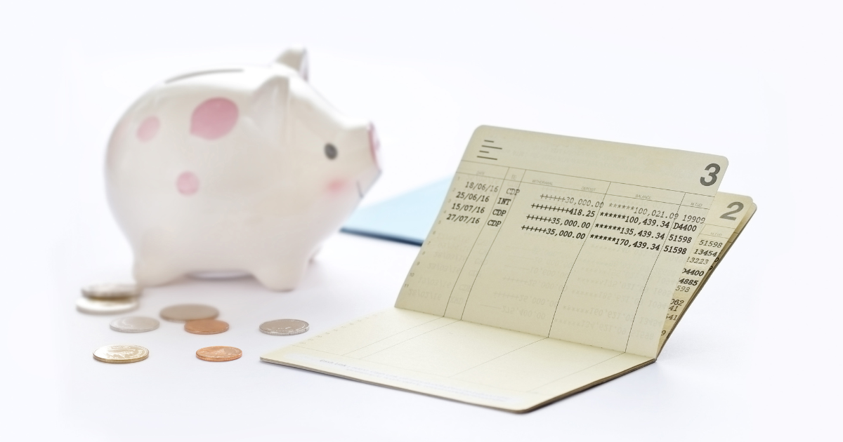 A piggy bank and scattered coins on a table, with an open passbook nearby. Our tax accountants in Sydney can help you plan and track your finances effectively.