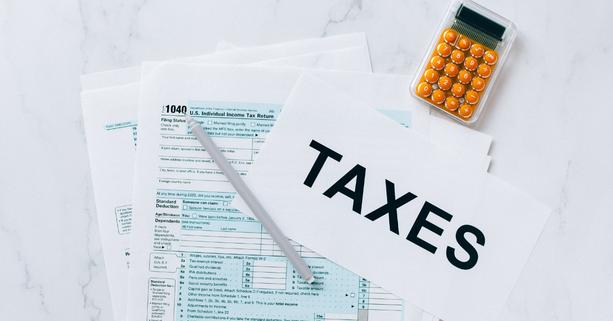 Tax documents with a pen resting on top and a calculator nearby. Let our tax accountants help you maximize your deductions and minimize your tax burden.