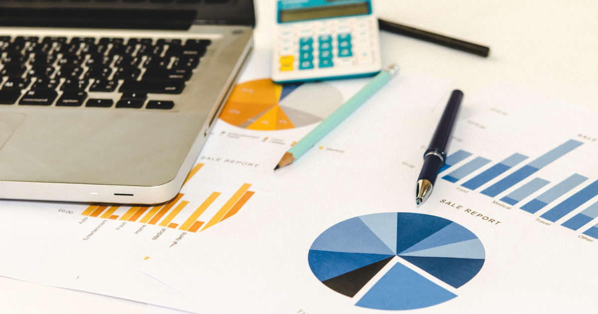 A laptop, calculator, and pens resting on a pile of financial data documents. Our accounting firm in Sydney can help you make sense of your financial data and manage your bookkeeping and accounting needs.