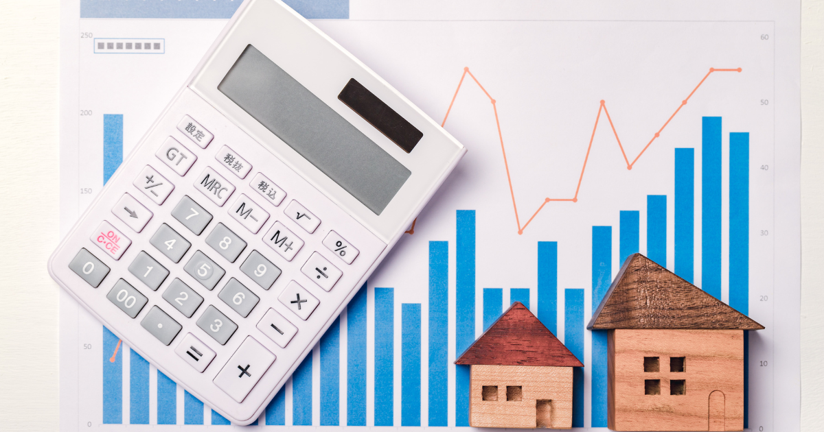 A calculator and miniature houses on a table with financial data analysis results in the background. Let our team of business accountants in Sydney help you with investment strategies and wealth management.
