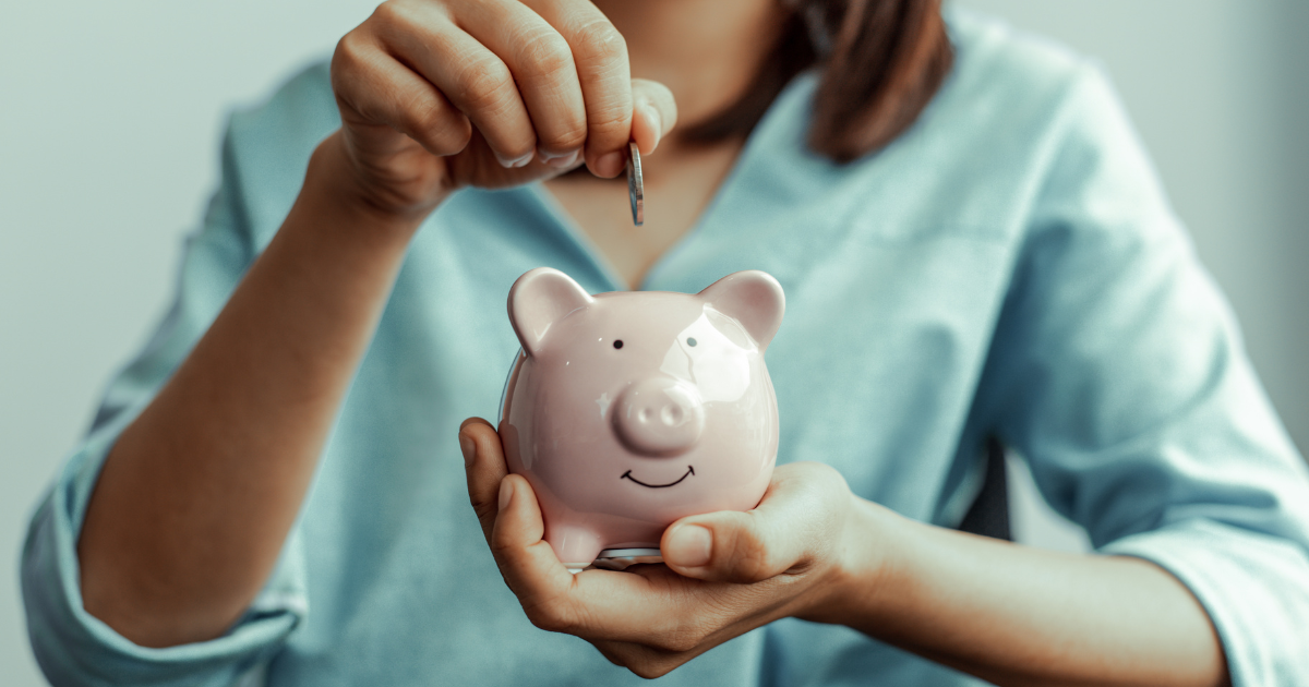 A woman is preparing to save money by putting a coin in a piggy bank, a practice advised by bookkeeping in Sydney.