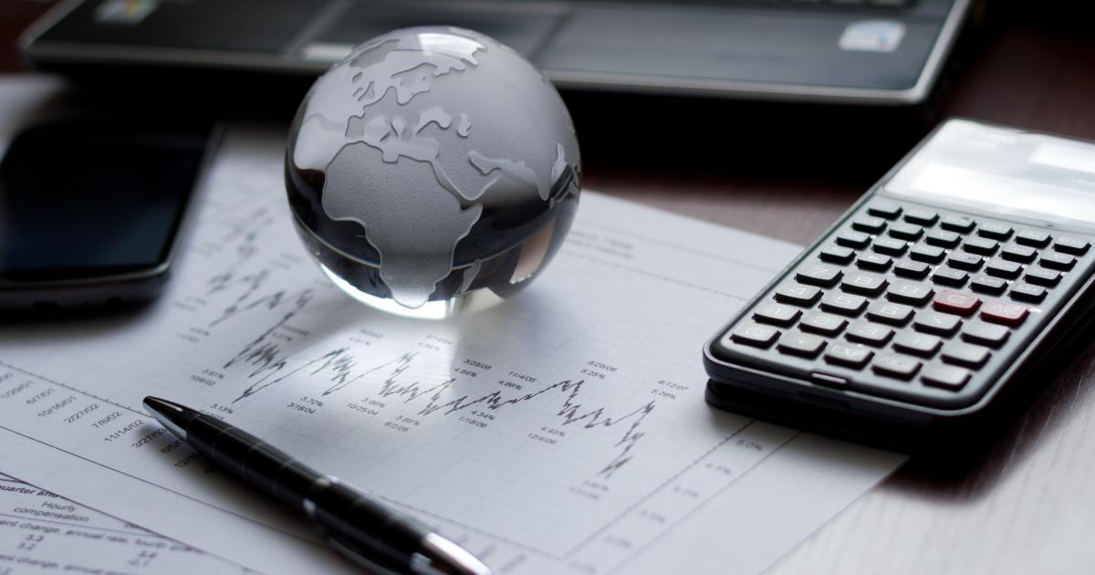 A globe, calculator, and financial analysis document on a table. Contact our accounting firm for expert advice on navigating the complexities of global finance.