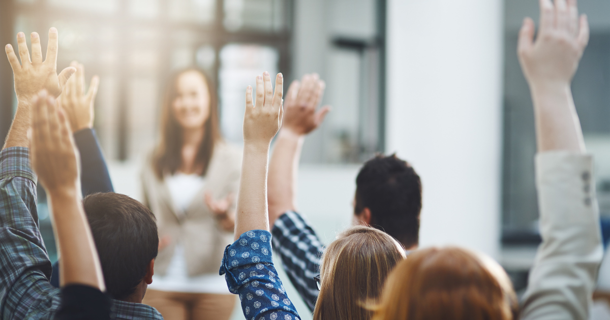 A group of people raising their hands in a meeting, representing participation and engagement in a collaborative environment. Contact our accounting firm in Sydney for personalised financial advice and support, and let us help you achieve your financial goals.