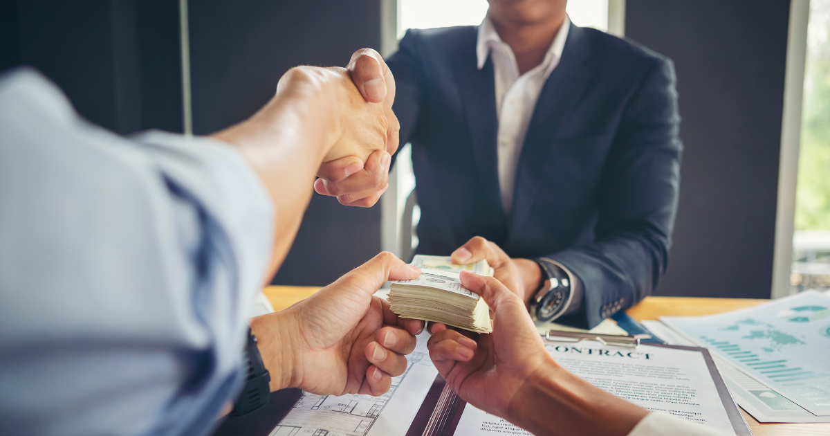 Tax accountants signing financial documents and completing a money transaction with a contract on the table.