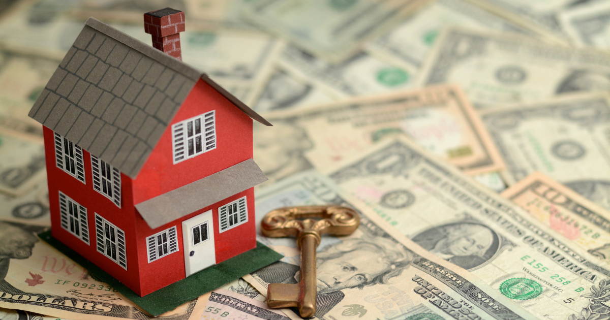 A key and a small house resting on top of scattered dollar bills, representing the concept of real estate investment and financial stability. Contact our accounting firm in Sydney for expert advice on managing your real estate investments and finances.