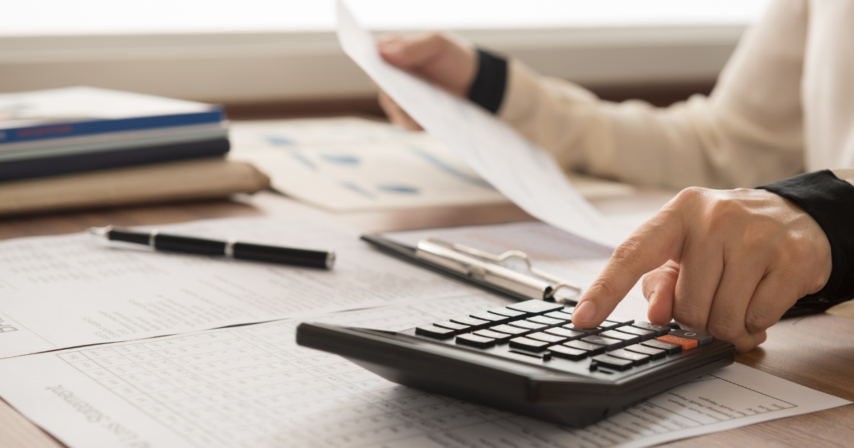 Hands typing on a calculator while another hand holds a document for analysis. Contact our accounting firm in Sydney for expert financial analysis and advice.