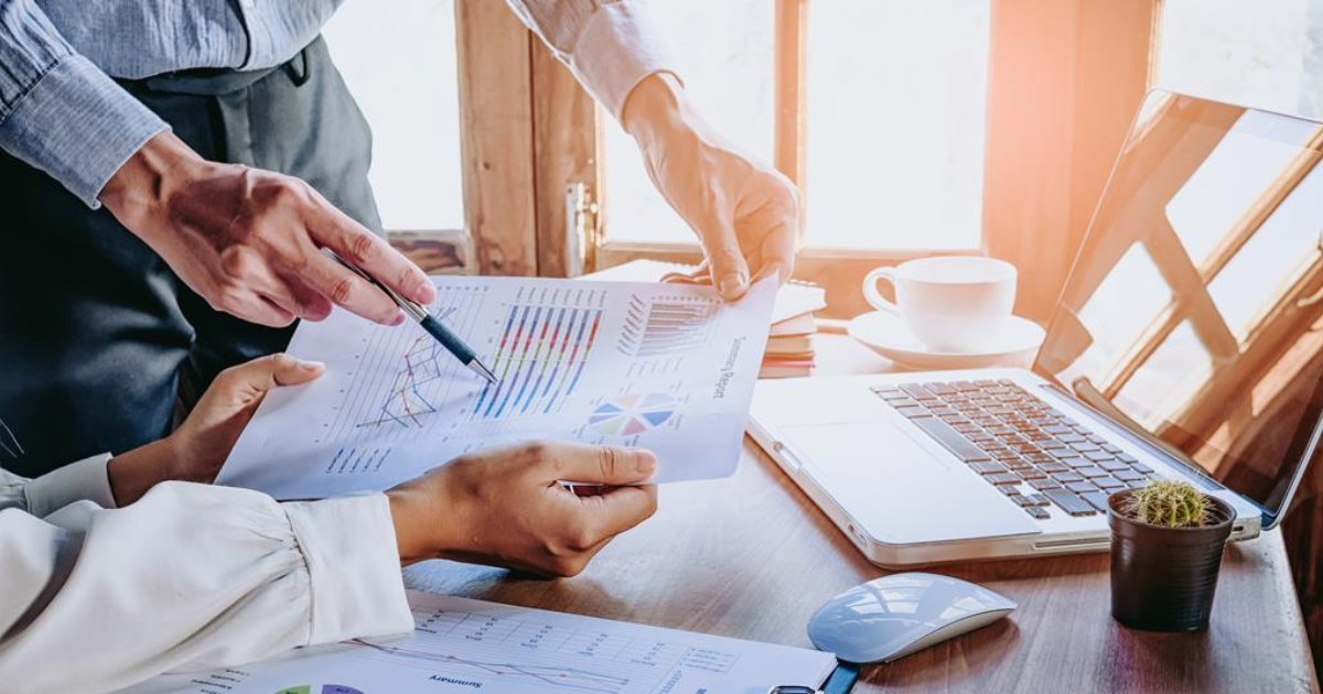 Two persons are discussing financial data analysis, with a laptop and other financial documents visible on the table. Contact our small business accountants in Sydney for expert financial advice and support to help you optimise your financial strategy.